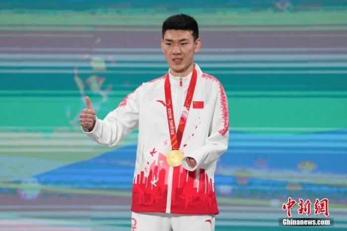 3月6日，梁景怡在延慶頒獎廣場領獎臺上豎起大拇指。當日，在國家高山滑雪中心舉行的北京2022年冬殘奧會殘奧高山滑雪男子超級大回轉—站姿決賽中，中國選手梁景怡奪得冠軍。 <a target='_blank' href='/'>中新社</a>記者 楊華峰 攝