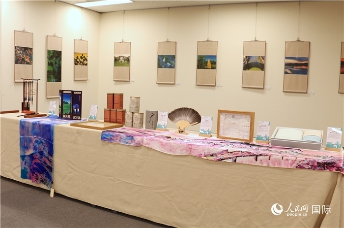 現(xiàn)場展出的馮學(xué)敏攝影作品與湖州市特色工藝品。（人民網(wǎng) 許可攝）