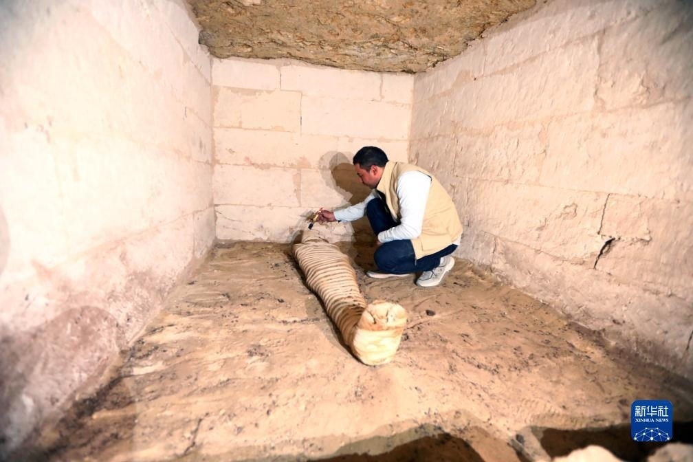 10月15日，在埃及明亞省考古現(xiàn)場(chǎng)，考古人員清理一座石鑿墓中的木乃伊。新華社發(fā)（艾哈邁德·戈馬攝）