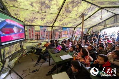 12月22日，在積石山縣大河家鎮(zhèn)大河村安置點(diǎn)，陸軍76集團(tuán)軍某旅搭建的“臨時(shí)學(xué)?！眱?nèi)，小朋友正在看動畫片。人民網(wǎng)記者 翁奇羽攝