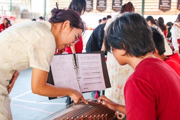 志愿者教師指導(dǎo)學(xué)生彈奏古箏?；顒又鬓k方供圖