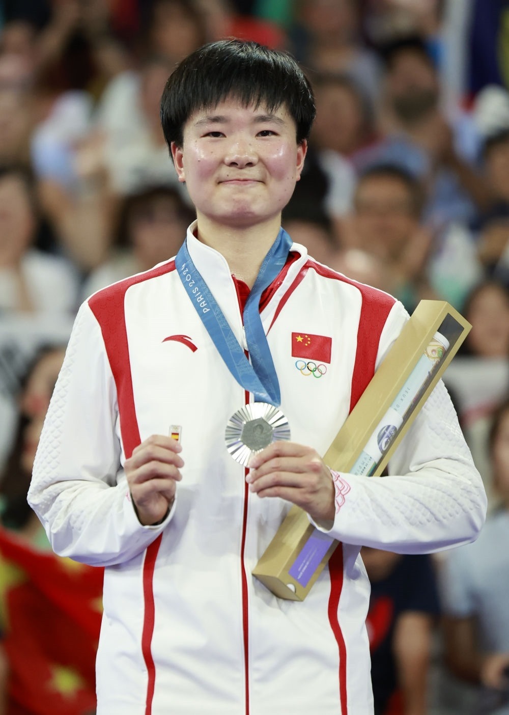 巴黎奧運(yùn)會(huì)羽毛球女子單打亞軍、中國(guó)選手何冰嬌在頒獎(jiǎng)儀式上一手握著銀牌，一手握著西班牙奧委會(huì)徽章（2024年8月5日攝）。新華社記者 任正來(lái) 攝