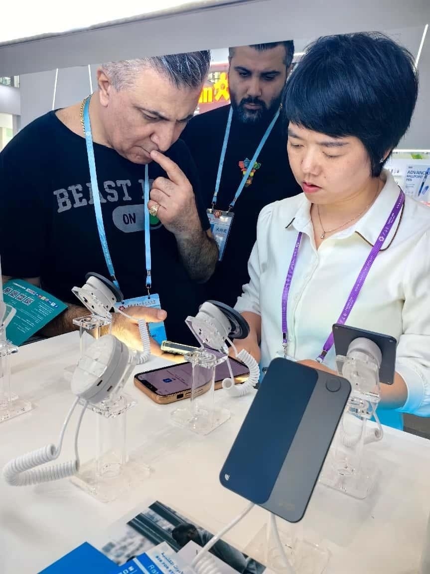 展臺(tái)工作人員向外商展示“AI TOP翻譯終端”。圖片來源：受訪者提供
