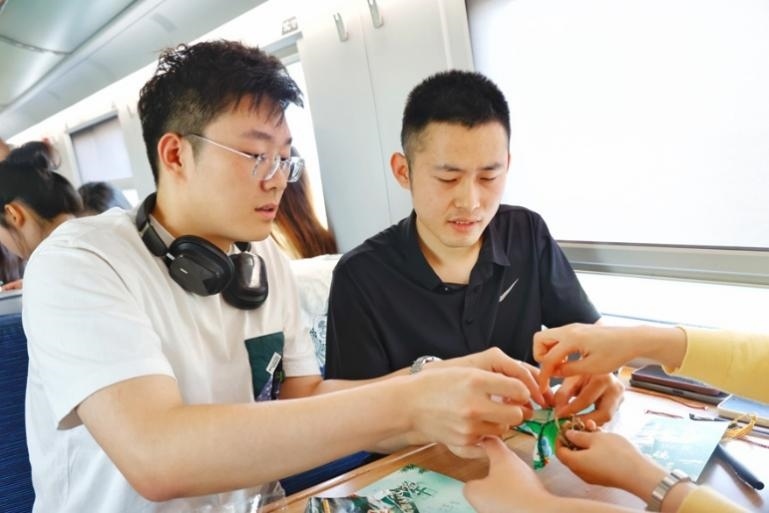 G232次旅客親手制作端午荷包和五彩繩。王磊攝